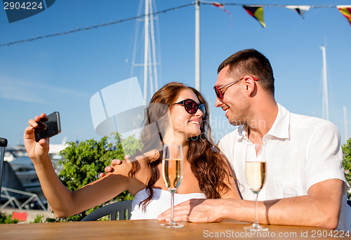 Image of smiling couple drinking champagne at cafe
