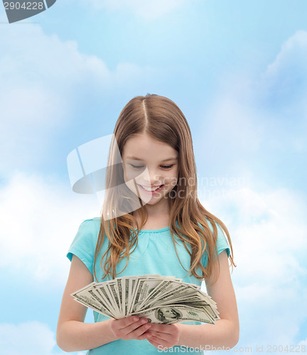 Image of smiling little girl looking at dollar cash money