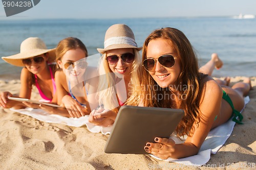 Image of group of smiling young women with tablets on beach