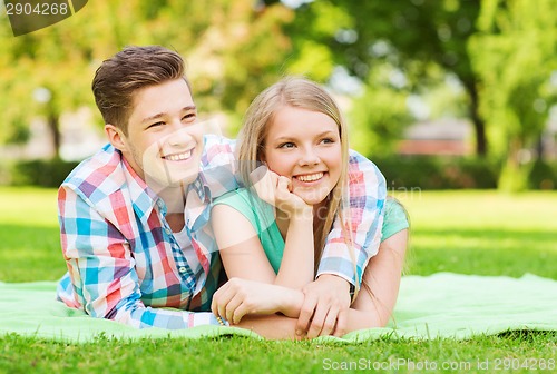 Image of smiling couple lying on blanket in park