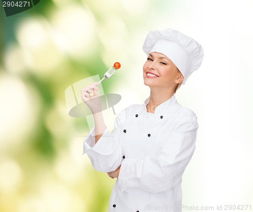 Image of smiling female chef with fork and tomato