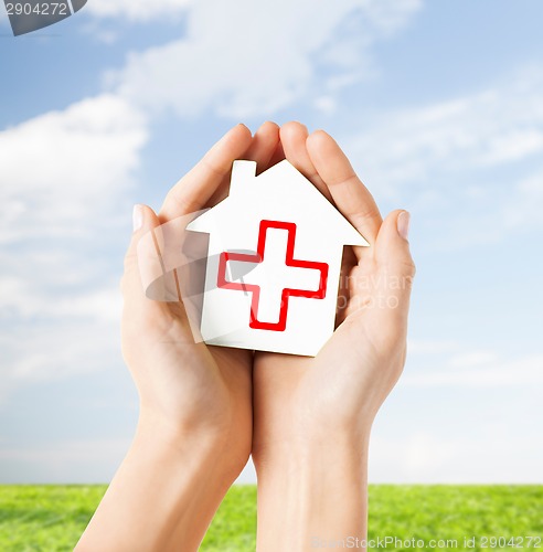 Image of hands holding paper house with red cross