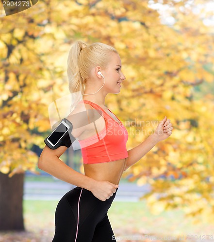 Image of sporty woman running with smartphone and earphones