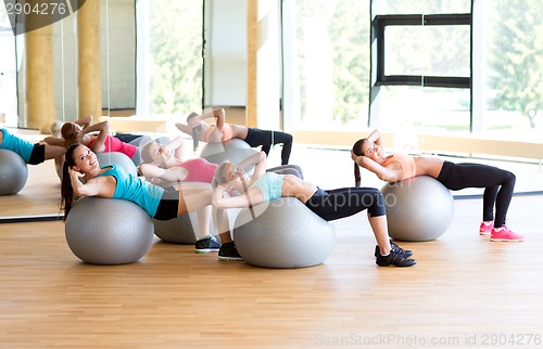 Image of group of smiling women with exercise balls in gym