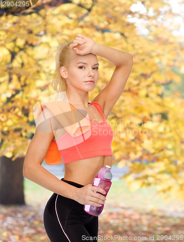 Image of tired sporty woman with towel and water bottle