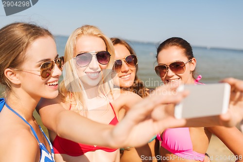 Image of group of smiling women making selfie on beach