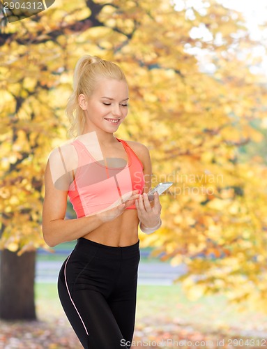 Image of smiling sporty woman with smartphone