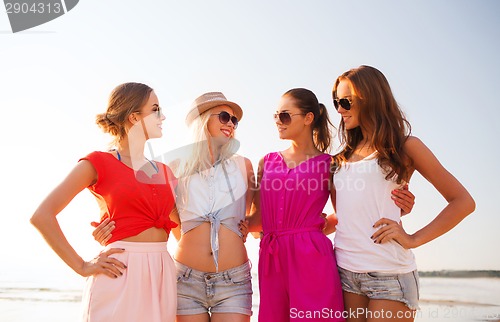 Image of group of smiling women in sunglasses on beach