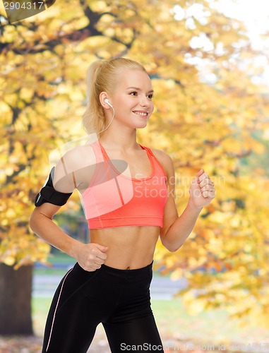 Image of sporty woman running with smartphone and earphones