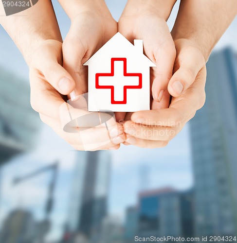 Image of hands holding paper house with red cross