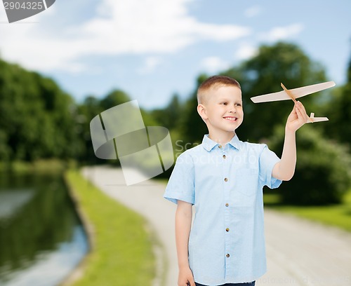 Image of smiling little boy holding a wooden airplane model