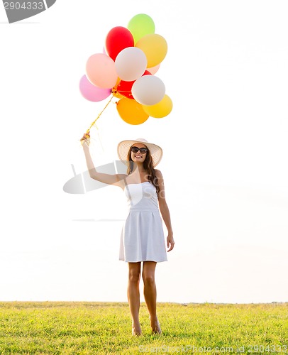 Image of smiling young woman in sunglasses with balloons