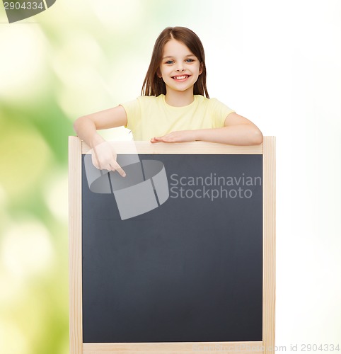 Image of happy little girl pointing finger to blackboard