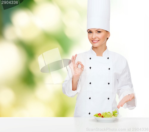 Image of smiling female chef with salad on plate