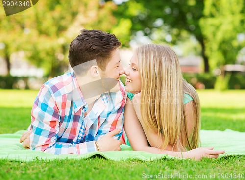 Image of smiling couple lying on blanket in park