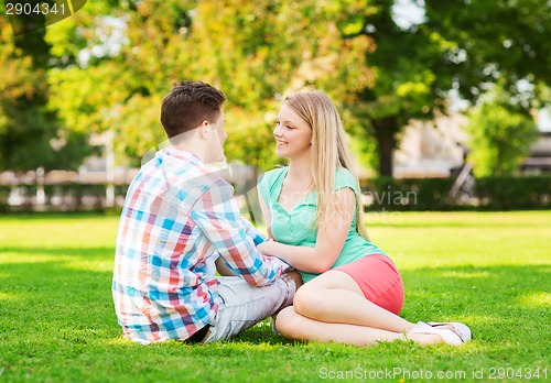 Image of smiling couple sitting on grass in park