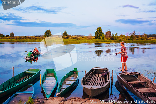 Image of Belarusian Boy Fishing From Old Boats At Sunset Of A Summer Day