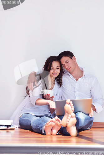 Image of relaxed young couple working on laptop computer at home