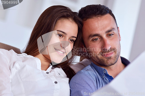 Image of relaxed young couple working on laptop computer at home