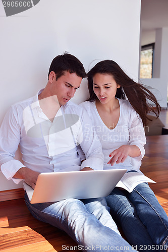 Image of relaxed young couple working on laptop computer at home