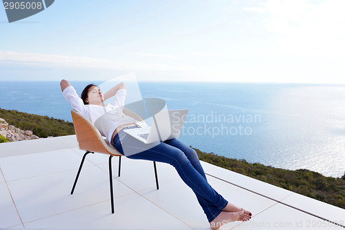 Image of relaxed young woman at home working on laptop