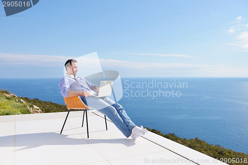 Image of relaxed young man at home on balcony