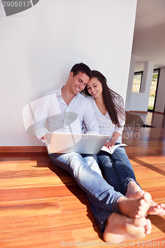 Image of relaxed young couple working on laptop computer at home