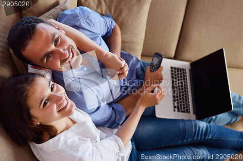 Image of relaxed young couple working on laptop computer at home