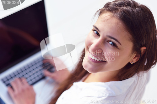 Image of relaxed young woman at home working on laptop computer