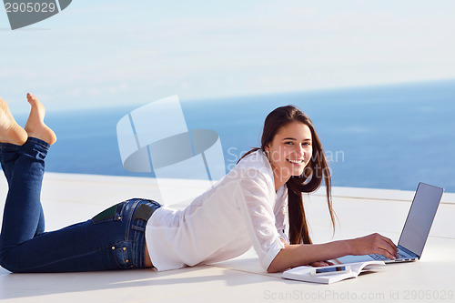 Image of relaxed young woman at home working on laptop computer