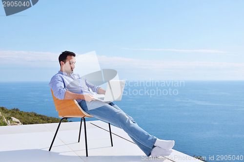 Image of relaxed young man at home on balcony