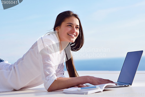 Image of relaxed young woman at home working on laptop computer