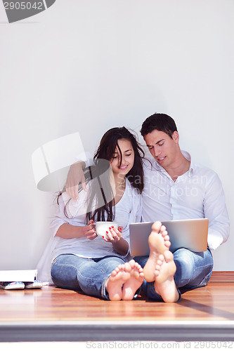 Image of relaxed young couple working on laptop computer at home