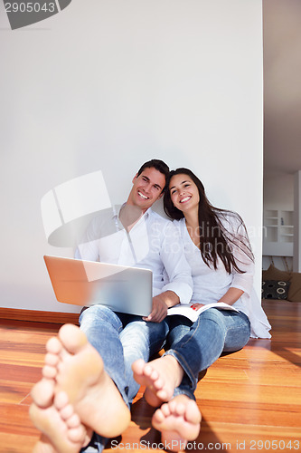 Image of relaxed young couple working on laptop computer at home