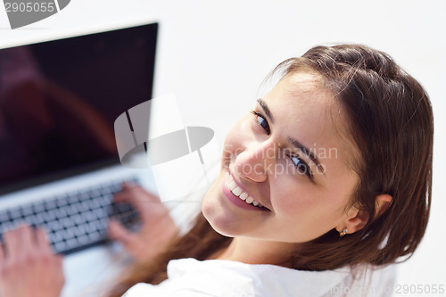 Image of relaxed young woman at home working on laptop computer