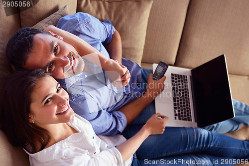 Image of relaxed young couple working on laptop computer at home