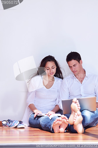 Image of relaxed young couple working on laptop computer at home