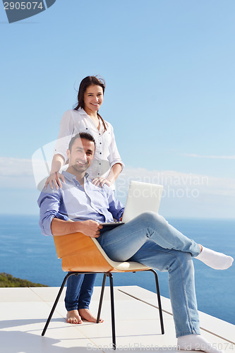Image of relaxed young couple working on laptop computer at home