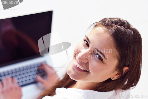 Image of relaxed young woman at home working on laptop computer