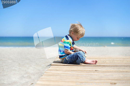 Image of Boy sitting on a wooden walkway on the beach