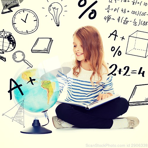 Image of child looking at globe and holding book