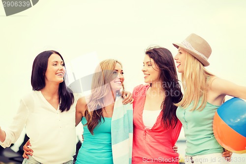 Image of smiling girls with ball and towel on the beach