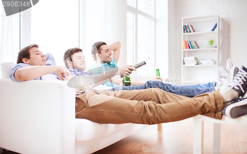 Image of happy male friends with beer watching tv at home