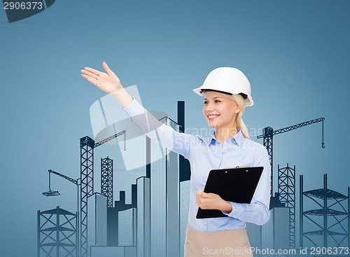 Image of smiling businesswoman in helmet with clipboard