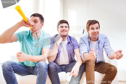 Image of happy male friends with vuvuzela