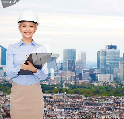 Image of smiling businesswoman in helmet with clipboard