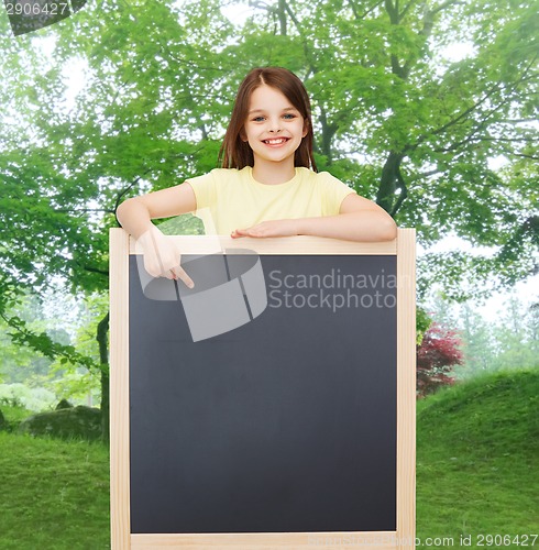 Image of happy little girl pointing finger to blackboard