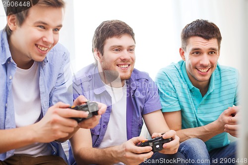 Image of smiling friends playing video games at home