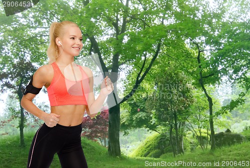 Image of sporty woman running with smartphone and earphones