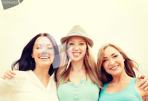 Image of group of smiling girls chilling on the beach